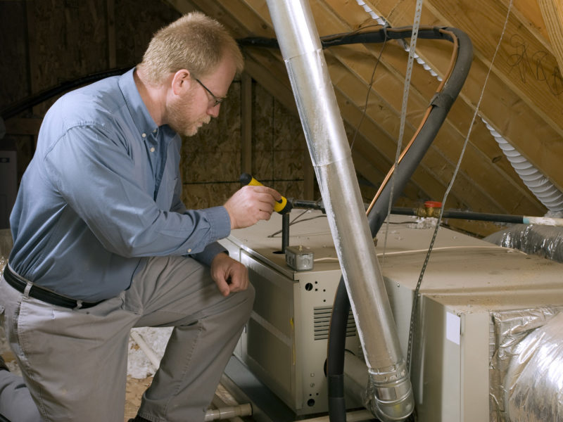 HVAC technician inspecting a home furnace in an attic
