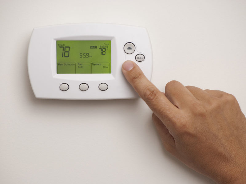 Male hand on Digital Thermostat